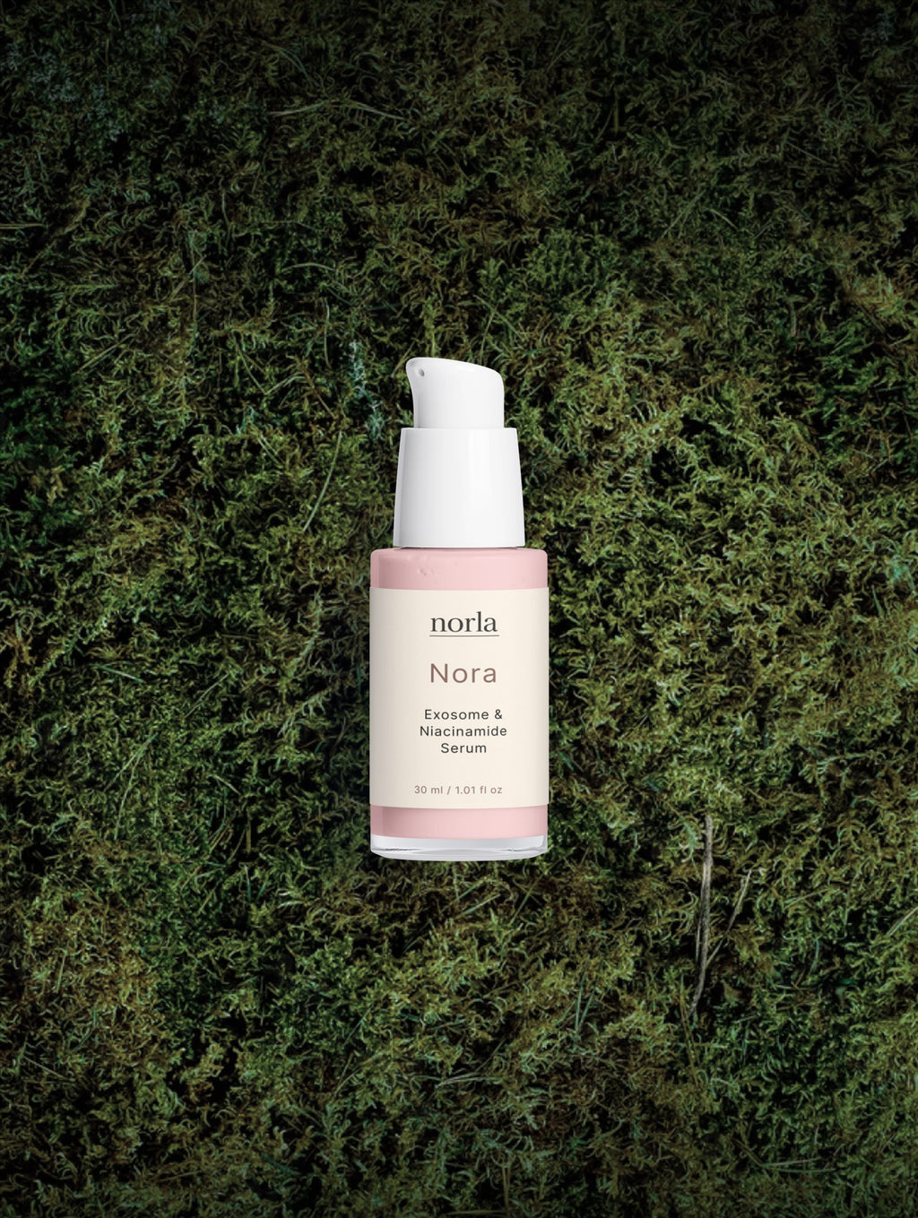 Nora — Exosome & Niacinamide Serum by Norla resting on green moss